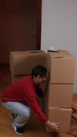 A man bending over to pick up a stack of boxes video
