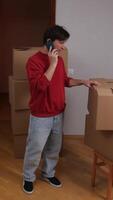 A man talking on a cell phone while standing next to boxes video