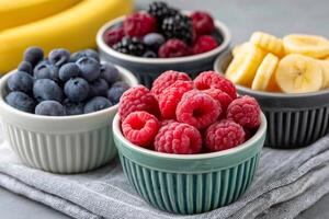 Frozen raspberries, blueberries, blackberries and banana slices in bowls, creating a colorful and healthy snack or breakfast option photo