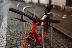 Handlebar View of an Orange Bicycle on Wet Cobblestones photo
