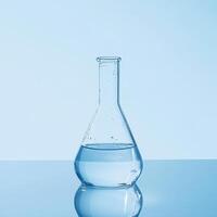 Clear glass flask with water on reflective surface photo