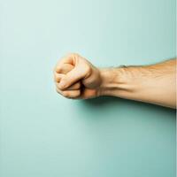 Strong fist raised against a light blue background photo