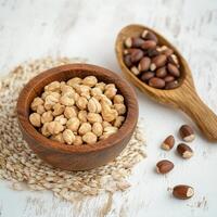 Chickpeas and peanuts in wooden bowls on table photo