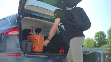 Man loading suitcases, bag and backpack into car trunk video