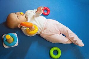 The child plays on the pyramid lying on the floor photo