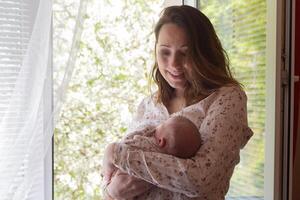 A happy mother with a newborn baby in her arms by the window.. People photo