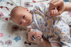 A charming newborn child will be by the hands of his mother photo
