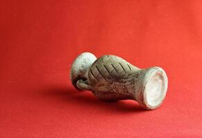 Antique ceramic decorative amphora on a red background. Clay pot, a set of antique utensils for gardening and interior photo