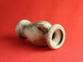 Antique ceramic decorative amphora on red background. The clay pot, set of antique utensils for gardening and interior photo