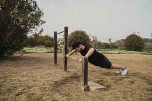 Man Does Push Ups Sport Exercise In The Park Using The Iron Bar Outside photo