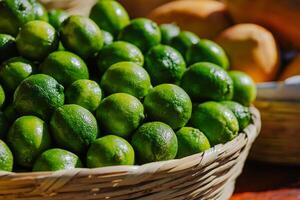 A close-up of fresh green limes in a woven basket, displayed under natural light at a market stand. Perfect for use in food-related content, gastronomy, nutrition, and local agriculture promotions. photo