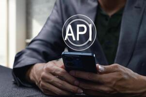Hands Holding Smartphone with API Symbol in Business Setting photo