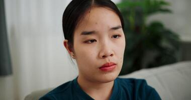 Handheld selective focus shot, Lonely woman sits on a sofa, lost in her thoughts and life problems in a quiet room. video