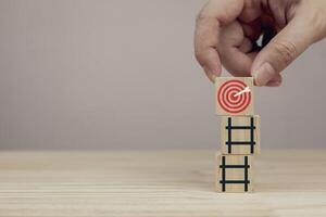 Hand placing wooden blocks with red dartboard on stairs. Concept of business strategy planning and goal setting, with copy space photo