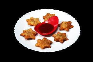 Flaky Star-Shaped Aloo Puff Pastries with Rich Tomato Sauce Resting on Black Marble - A Perfect Snack for Parties and Tea-Time photo