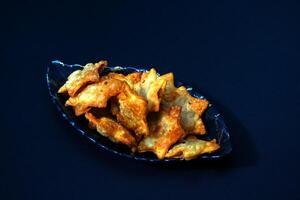 A clear glass bowl filled with golden-brown fried chicken wings, served with a rich tomato sauce for dipping. photo