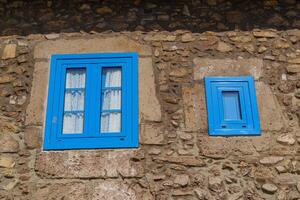 A stone wall with two blue windows photo