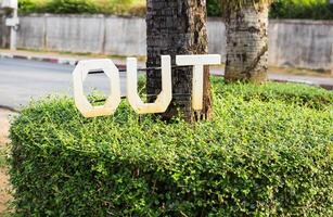 exit or out sign mounted on a green bush photo