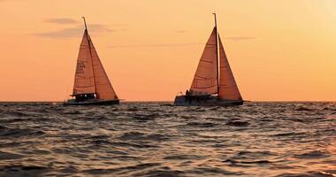 Slow motion footage of sailing regatta in the Gulf of Finland at sunset, two sailing yachts competing in a race, splashing water from under the boats, teamwork, board the boat video