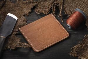 Making leather wallets. On a wooden table there is a wallet, photo