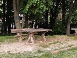Old wooden picnic bench in a shaded forest clearing. A quiet corner in nature for rest and conversation. photo