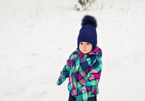 portrait of a little girl in winter clothes in snow forest at snowflakes background photo