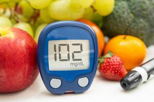 hand holding digital glucose monitor measure with vegetable photo