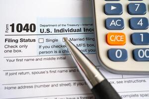 Tax Return form 1040 with pen and calculator, U.S. Individual Income. photo