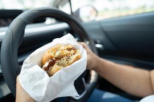 lady holding hamburger eat in car photo