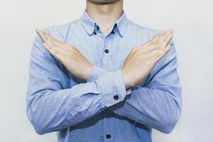 Man crossing arms in X gesture for stop, deny, protest, block, avoid, no access, restriction, warning, barrier, privacy, personal boundary, control, signal, disagreement. Isolated on white background. photo