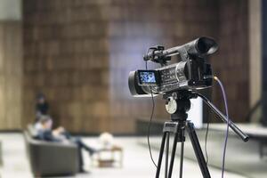Broadcast camera with tripod setup used during a live news interview. Perfect for journalism, media reporting, television production, communication-related content in digital or corporate environments photo