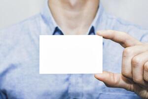 Closeup of a man holding a blank white business card, ideal for branding, marketing, and corporate identity presentation. Simple and clean mockup for contact, networking, and communication concept photo