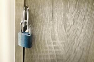 Close-up of key to lock or unlock a padlock on a wooden door, symbolizing security, privacy, and access control and confidential data, safe solutions for home or represents protection concept. photo