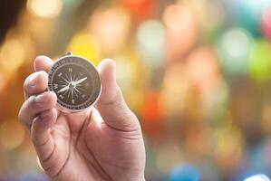 compass in hand on defocused abstract bokeh lights christmas background, blur of bokeh circle light christmas festive backdrop concept. photo