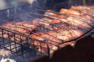 Pork meat grilling on barbecue grill with smoke photo