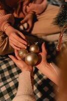 Close-up of hands gently holding golden Christmas ornaments during a quiet evening family ritual of decorating a tree with warm connection and thoughtful seasonal gestures Exchanging Christmas photo