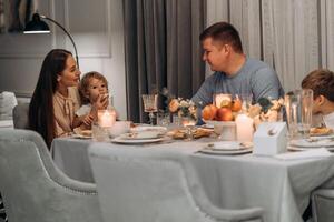 Mother and father engage with children during calm family dinner as toddler sits on mothers lap eating bread surrounded by warm candlelight soft tones and emotional presence in cozy home atmosphere of photo
