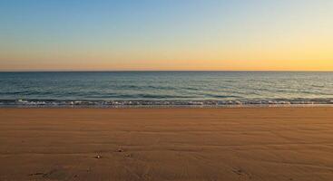 Serene beach scene at sunset with golden sand, ocean waves, and a gradient sky. photo