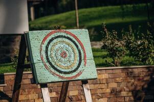 Close up view of dart holes on board due to throwing darts a bunch of times, outdoors, sunlight photo