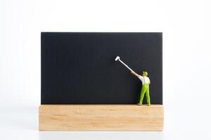 Tiny figurine painters writing on a blackboard on white background photo