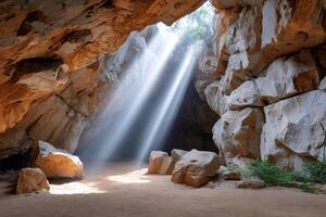 Sun rays illuminating cave with rocks and sand photo