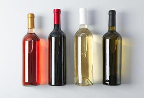 Bottles with different wine on grey background, top view photo