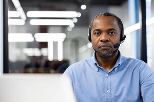 Mature african american businessman wearing headset in professional setting. Engaged in or phone call. Captured with focus on expression and professional attire, adding dynamic context. photo