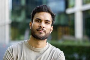 A portrait of a young man with a beard and a neutral expression, possibly after exercising. Urban background. photo