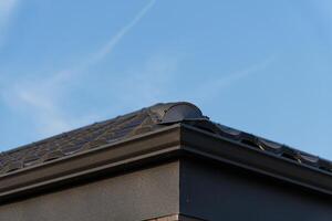 Detail of a metallic roof with unique tile design, emphasizing durability and artistry under a bright blue sky photo