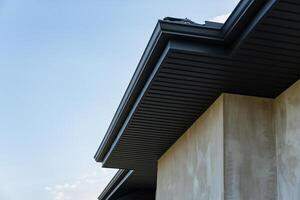 A close view of a metallic tile roofing installation on a modern building, showcasing craftsmanship and design under a bright sky photo