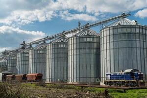 Tall silos stand at a grain storage facility, filled with harvested crops and situated alongside a railway, showcasing the farming industry photo
