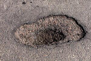 Large hole in the asphalt is evident on the highway, indicating significant damage that requires urgent repair to ensure safety for all vehicles photo