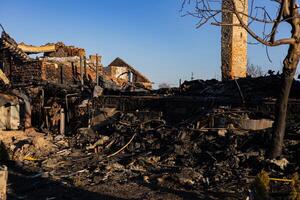 Ruins of a burned building reveal charred remains and debris, illustrating the impact of a recent fire in a rural setting during daylight photo