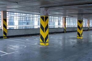 Interior view of an underground parking garage with safety markers, showcasing empty parking spaces and supporting columns photo